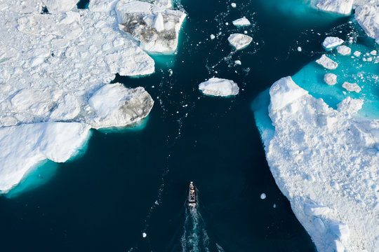 Aerial view of Small boat making a way through icebergs in Greenland