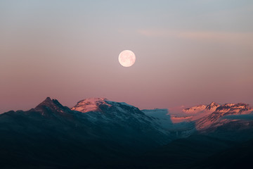 Moon rising over mountains during a dramatic sunset in Iceland