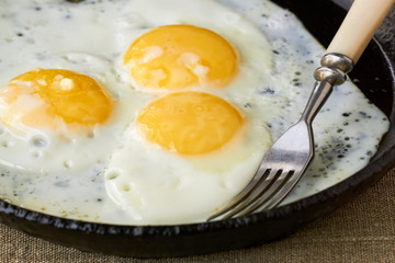 Fried eggs in a cast iron pan on a textile background