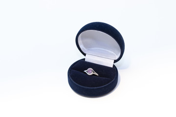 Silver ring with purple gemstone in a blue jewelry box on white background