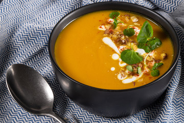 Pumpkin soup with watercress on table. Seasonal autumn food - Spicy pumpkin soup in bowl.