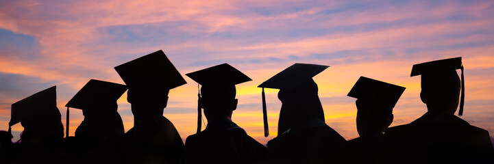 Fototapeta Silhouettes of students with graduate caps in a row on sunset background. Graduation ceremony at university web banner. obraz