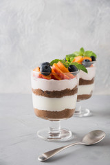 Puff dessert made of chocolate biscuit, cream cheese garnished with fresh apricot on light table. Close up.