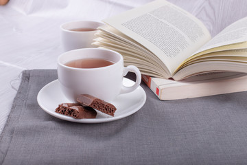 Book, cup of tea and chocolate on the table