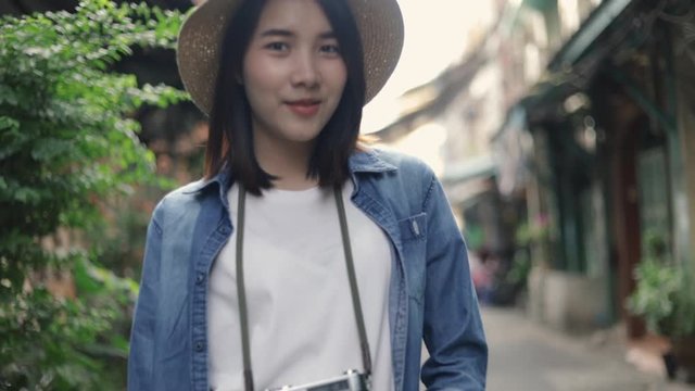 Portrait of beautiful hipster woman wearing retro fedora hat standing at a small street in Bangkok Thailand enjoying South East Asia summer holiday travel vacation.