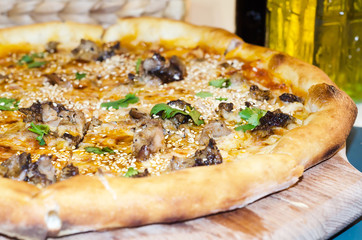 Italian pizza with mushrooms chapminions, duck breast and sesame seeds in restaurant
