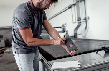 Young engineer setup plasma cutter for work in metalwork workshop.