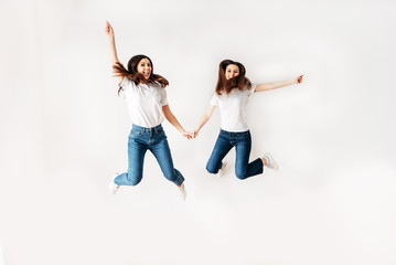 Two girls in casual clothes jump high