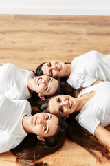 Cheerful girls in casual outfits lie on the floor.