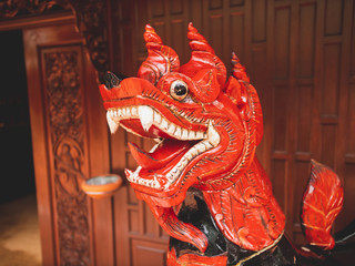 Closeup toned image of red dragon sculpture carved in wood at traditional thailand house