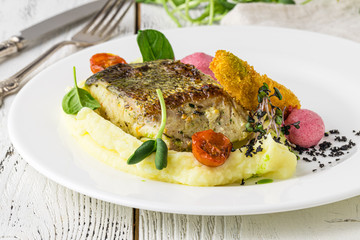 Food - Main course gourmet fish - delicious grilled golden sea bream or dorade with vegetable garnish served on a wooden tabl