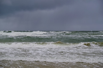 Rough sea with waves during autumn stormy weather. Black heavy clouds in the sky. Baltic Sea, Dziwnowek, Poland