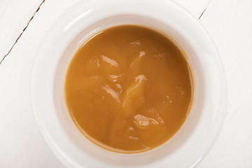 Top view of bowl with baby food on white wooden surface