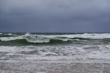 Fototapeta premium Rough sea with waves during autumn stormy weather. Black heavy clouds in the sky. Baltic Sea, Dziwnowek, Poland