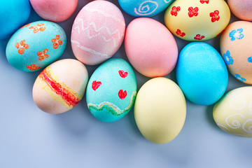 Colorful Easter eggs dyed by colored water with beautiful pattern on a pale blue background, design concept of holiday activity, top view, full frame.