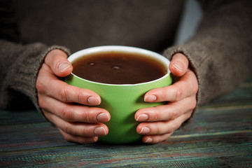 Woman holds a cup of hot tea. Cozy morning at home.