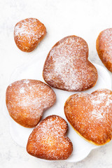 Homemade heart sheped donuts with powdered sugar on white background. Tasty doughnuts, copy space