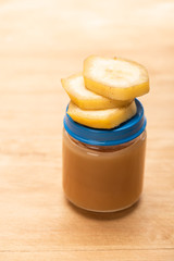 Close up view of jar with fruit nutrition and banana slices on wooden surface
