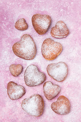 Homemade heart sheped donuts with powdered sugar on pnk background. Tasty doughnuts on cute pink pastel background