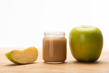Green apple with fruit baby nutrition in jar on wooden surface isolated on white