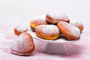 Homemade heart sheped donuts with powdered sugar on pnk background. Tasty doughnuts on cute pink pastel background
