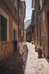 Young women in white dress is walking on Fornalutx street, Mallorca island, Balearic Islands, Spain