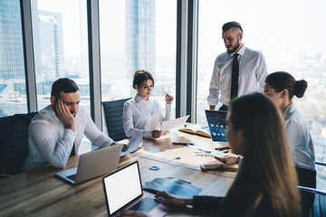Manager standing at table and making report to colleagues