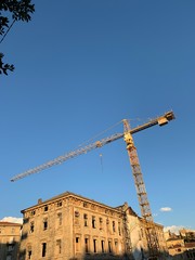 Yellow construction crane and reconstruction of old buildings, blue sky background