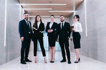 Merry coworkers standing in bright corridor