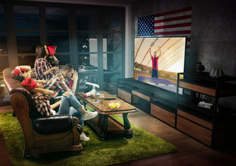 Group of friends watching TV, match, championship, sport games. Emotional men and women cheering for favourite table tennis player in America with flag. Concept of friendship, sport, competition.