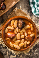 Typical Spanish fabada asturiana in crockpot on wooden table. Top view