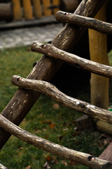 Naklejka premium DIY wooden playhouse for children with slide on a hillside in a sunny day. Modern unusual bright wooden playground children's lodge in forest. Children rest and childhood concept.