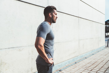 Serious sportsman relaxing after jog in urban street