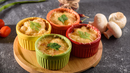closeup casserole with cheese in colorful cocoanuts with mushrooms and vegetables on gray background