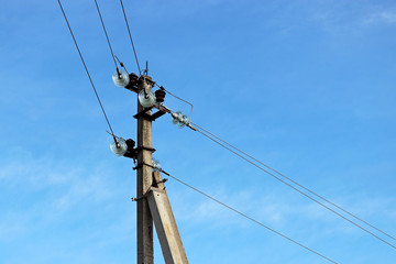 Power line post with electrical wires and capacitors isolated on blue sky background. Electricity transmission line, power supply