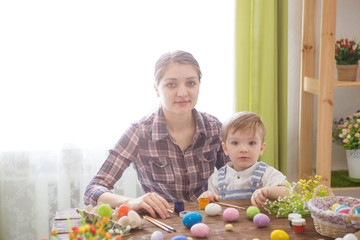 Mother and her son painting Easter eggs. Happy family preparing for Easter day
