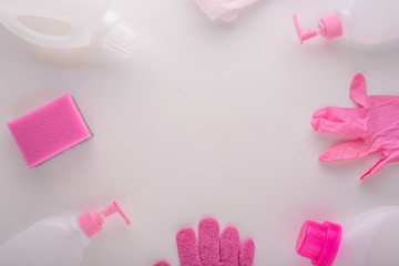 top view white and pink cleaning products-rubber gloves, sponge, plastic bottles for cleaning house on white background