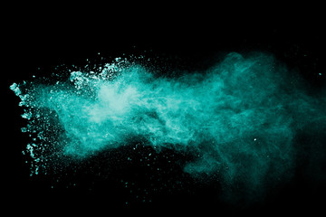 Abstract green dust splattered on black background. Freeze motion of green powder splash.
