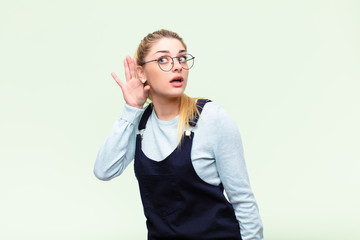 young pretty blonde woman looking serious and curious, listening, trying to hear a secret...
