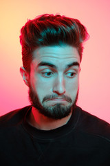 Beautiful caucasian young man portrait isolated on multicolored neon light backgroud. Young, smiling, surprised, screaming. Human emotions, facial expression concept. Trendy colors.Advertising concept