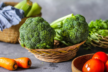 Photo of fresh broccoli around vegetables on cutting board. Raw Picture. Gray background. Image.