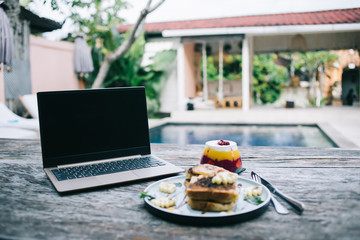 Standby laptop and tasty breakfast on table in yard