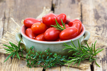 mini roma tomatoes and herbs on wooden background
