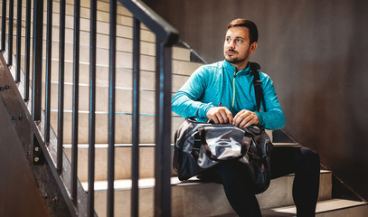 Happy fit man relaxing in the gym after strength exercises for different muscles