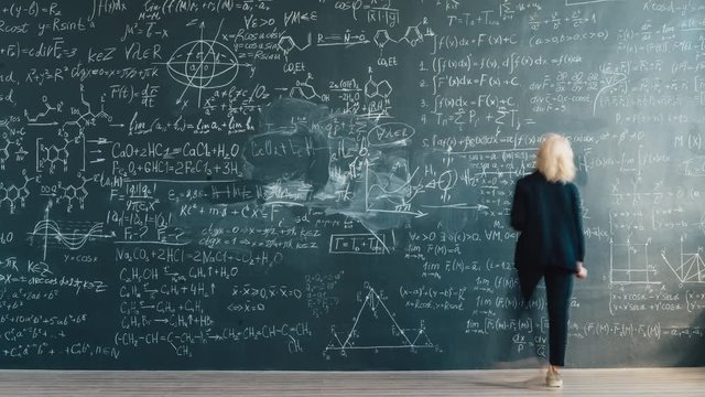 Time lapse back view of smart lady scientist writing formulas on chalkboard working alone at scientific project. Science, modern people and knowledge concept.
