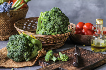 Photo of fresh broccoli around vegetables on cutting board. Raw Picture. Gray background. Image.