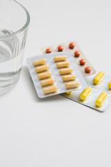 Pills and glass of water on white background.