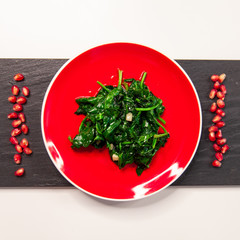 spinach dish on bright red plate. Vegan healthy food.