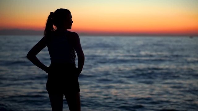 A Silhouette Of A Young Sexy Lady Standing At The Shore With The Majestic Sundown On Her Background - Medium Shot