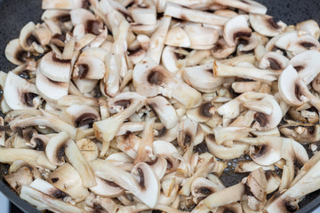 Cooking fresh mushrooms, close-up. Roasting sliced champignons. Fried mushrooms. Food background, top view